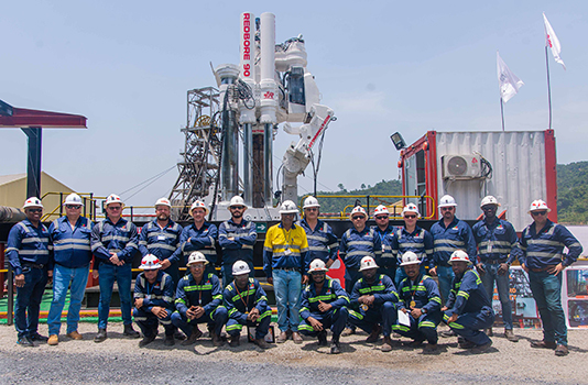 A large group of Redpath Africa employees standing in front of a Redbore 90 raisedrill.